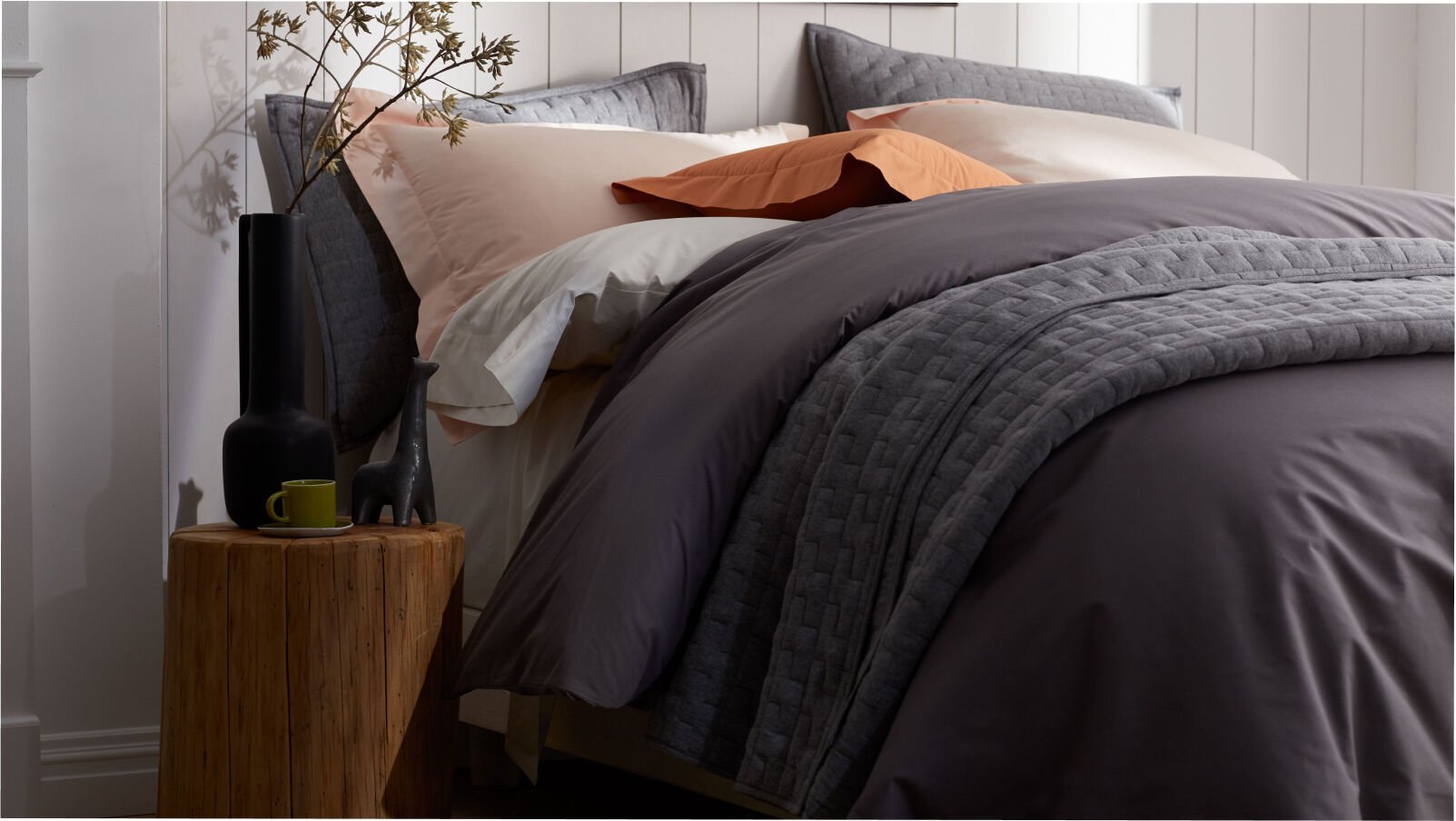 bed with gray sheets and gray quilt