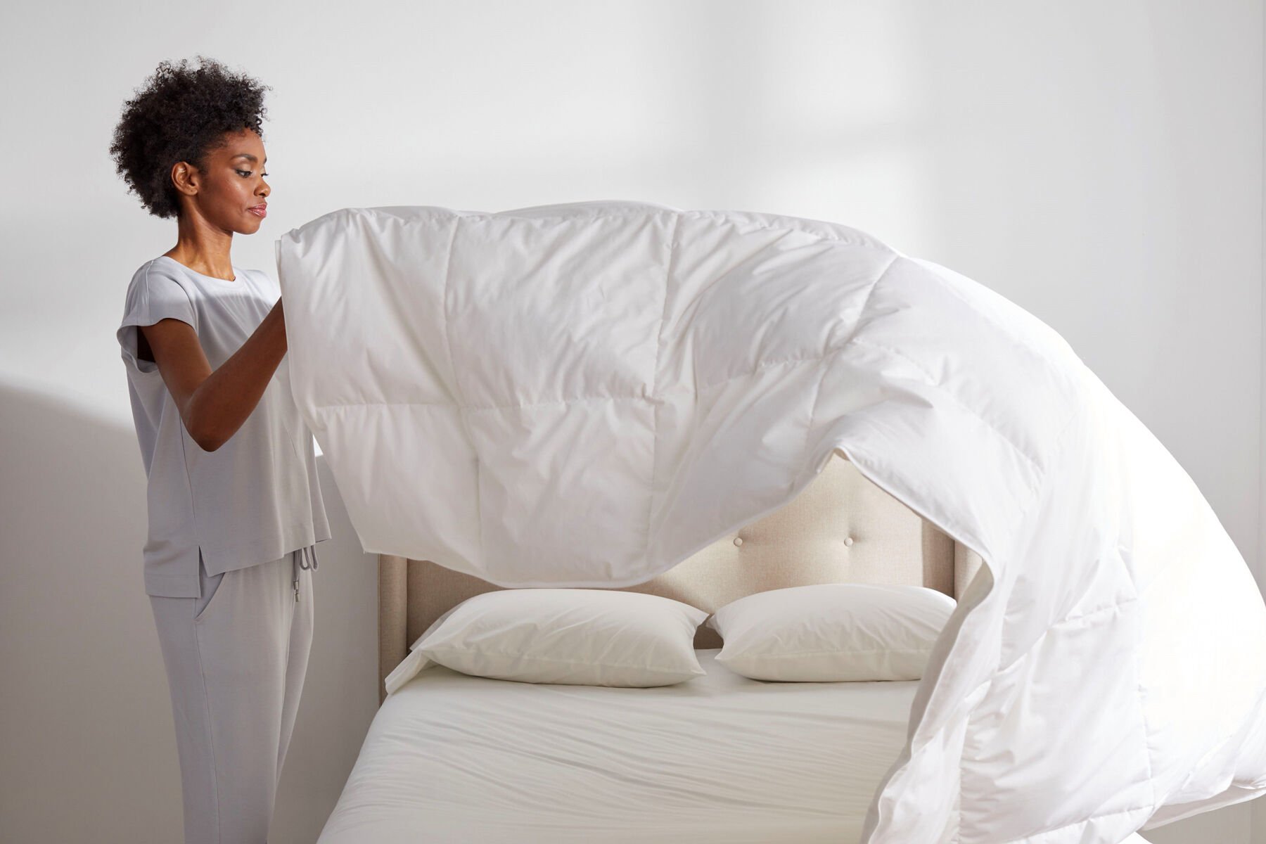 woman fluffing comforter woman fluffing comforter