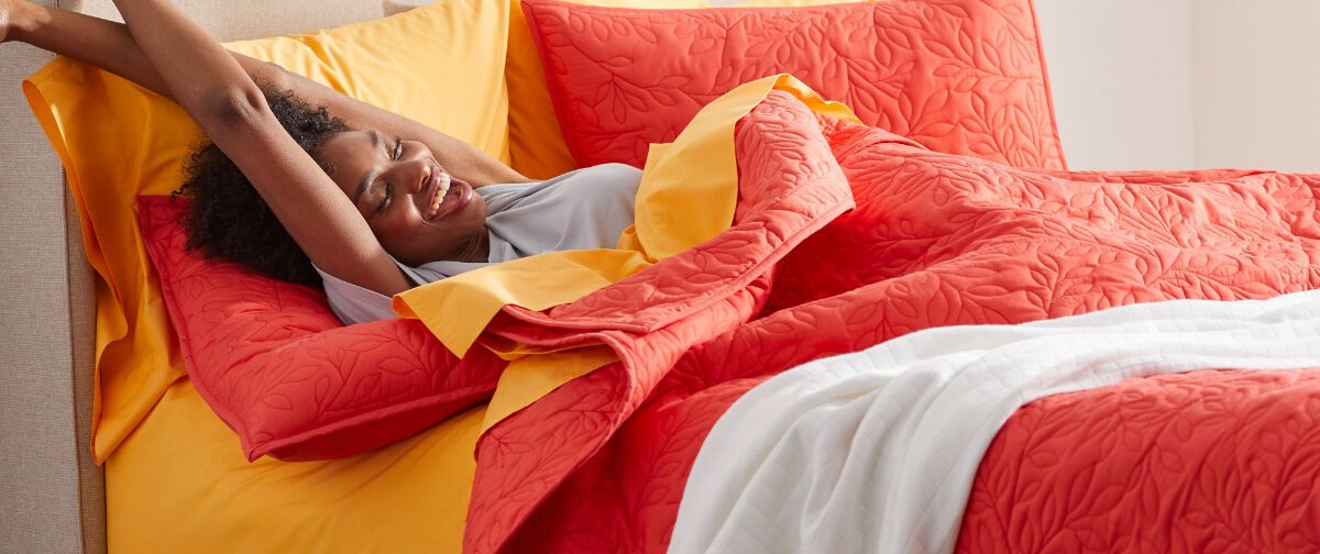 Woman stretching in a red and orange bed