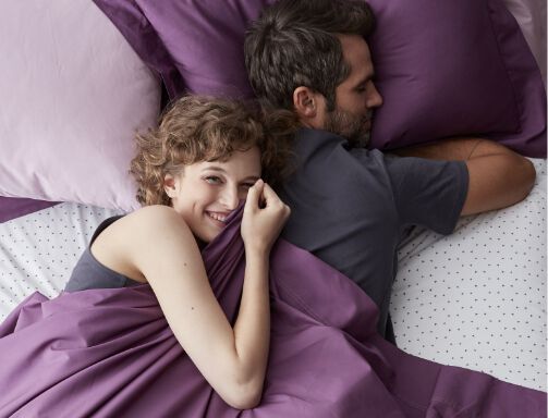 woman hugging man on purple bedding