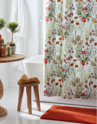 Image of a bathroom with a bright orange bath mat and floral shower curtain