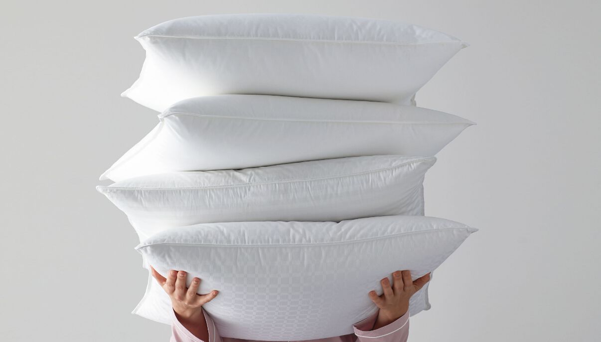 Person holding a stack of pillows